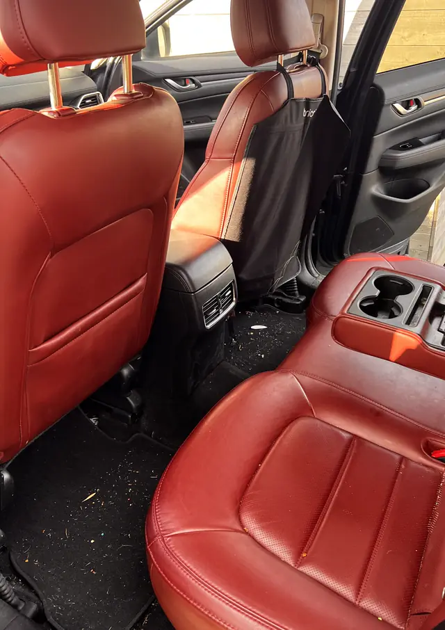 The same rear seats before the detail: crumbs and dirt across the carpet and seat.